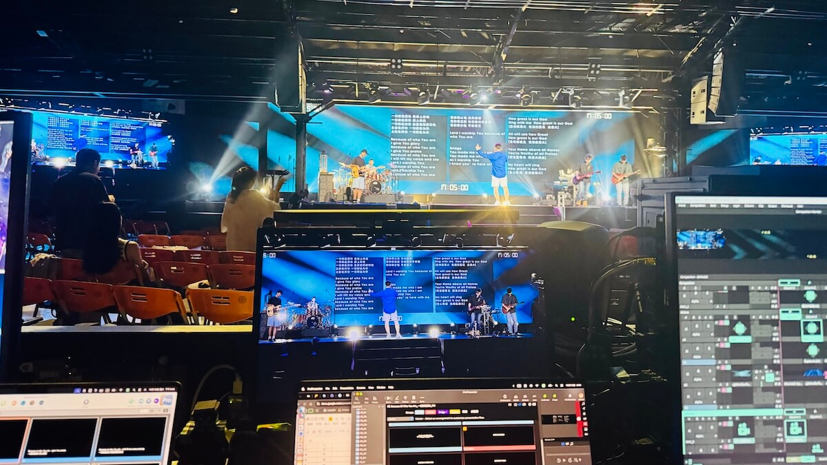 A worship venue with a main screen above the stage and two side screens